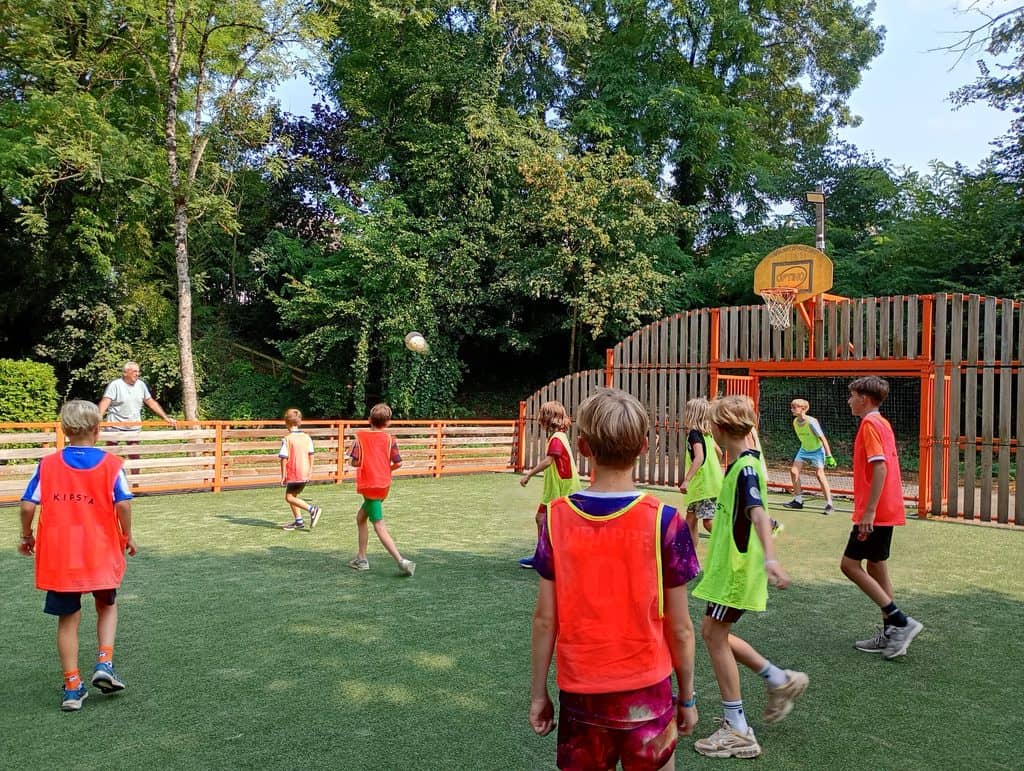 Enfants jouant au football sur terrain multisport en plein air