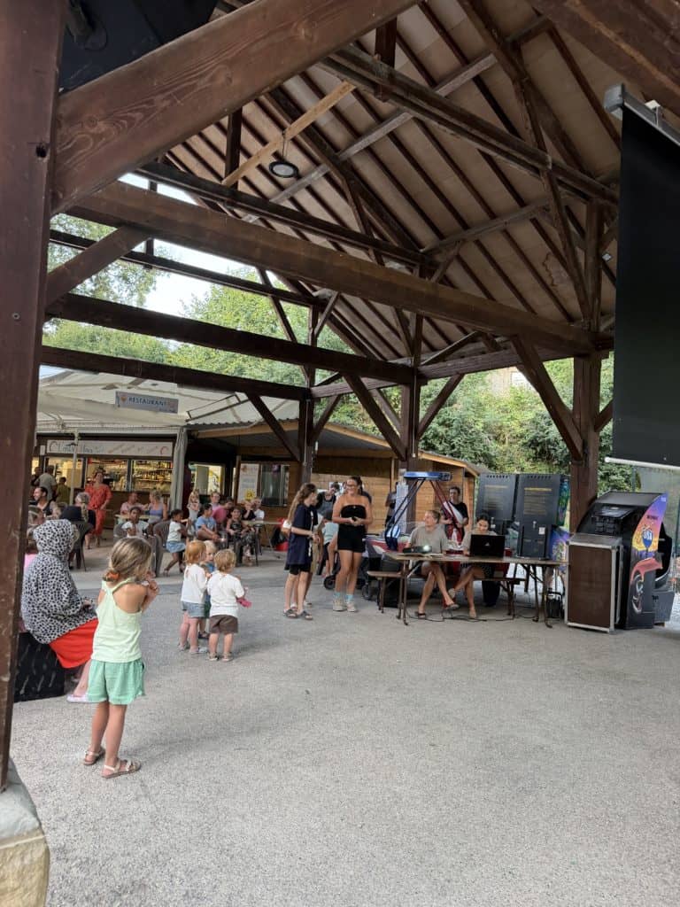 Animation estivale sous un préau en bois avec familles et enfants