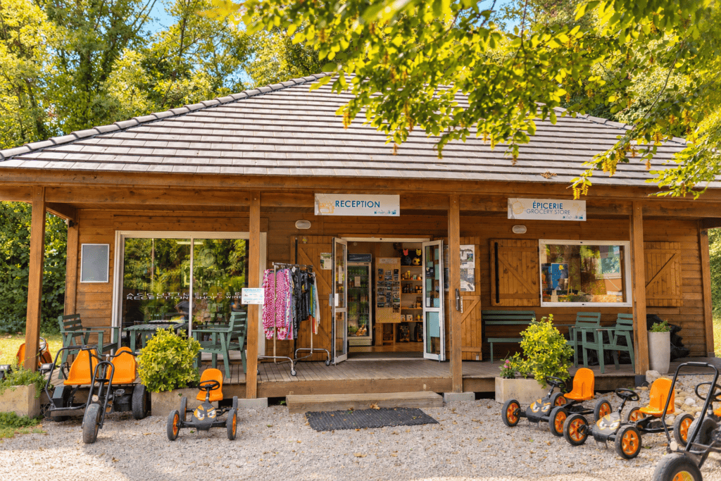 Réception et épicerie d'un camping en bois entouré de verdure