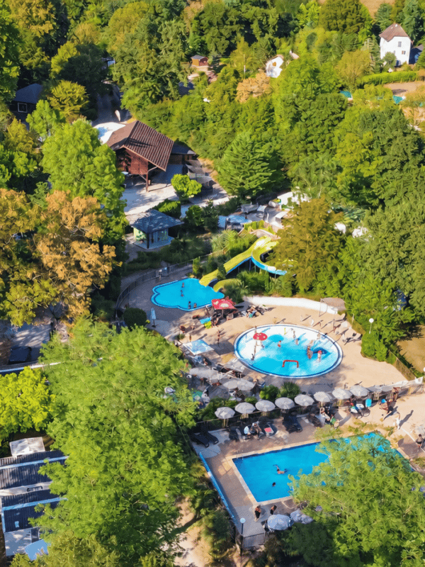 Vue aérienne d'un camping avec piscines entouré de forêt